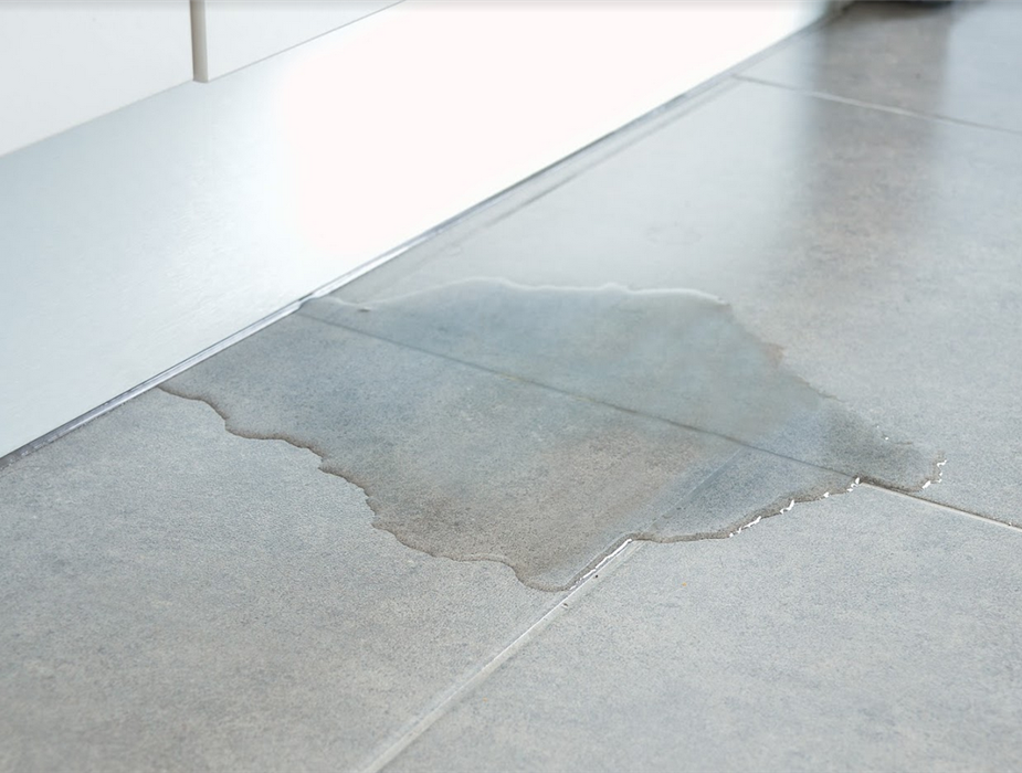 a puddle of water on the gray tile floor