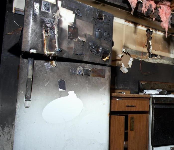 A fridge in a kitchen with soot on it.
