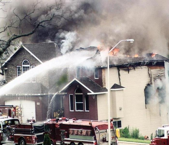 Fire fighters with water hitting a burning home