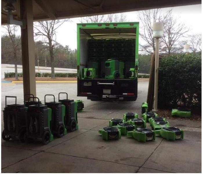 SERVPRO restoration vehicle open showing restoration equipment. Also, restoration equipment stacked on the ground