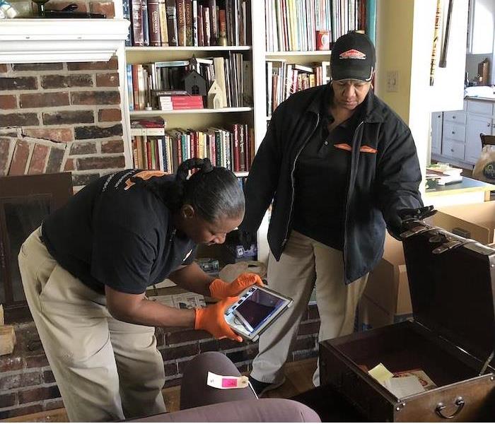 two employees documenting damaged items in a home